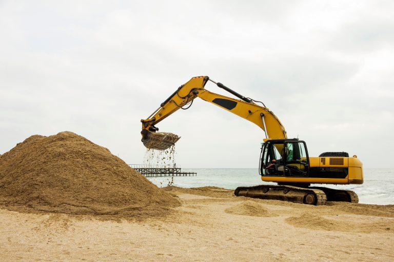 An,Excavator,Makes,A,Mound,Of,Sand,On,The,Seashore.