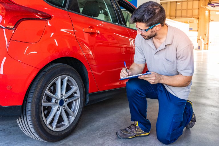 Technician,With,Safety,Glasses,Checking,The,Tires,Of,A,Red