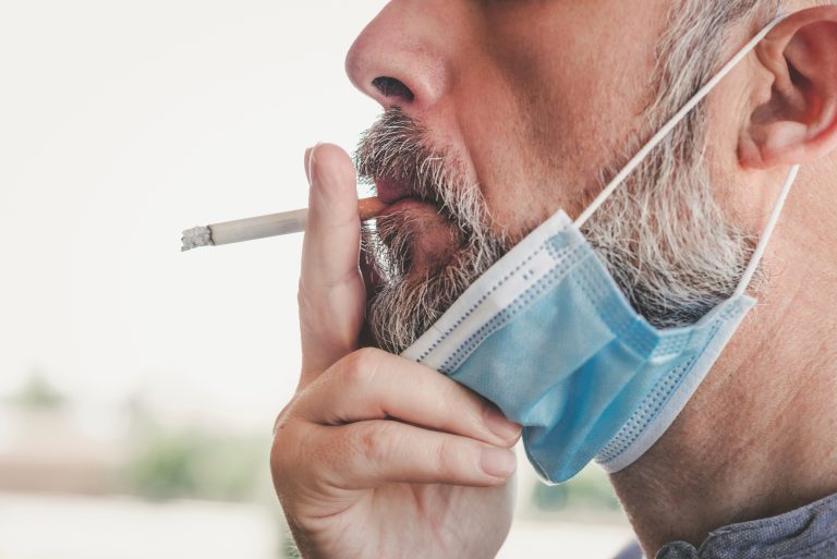 Covid-19,close-up,Of,Man,With,Medical,Mask,Smoking,A,Cigarette,At
