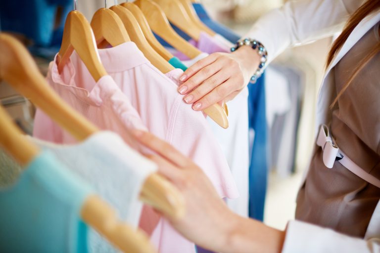 Young,Woman,Looking,Through,New,Clothes,During,Shopping