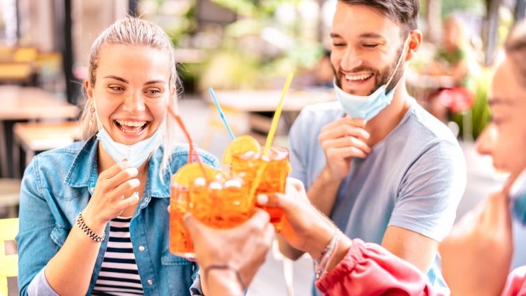 Friends,Drinking,At,Cocktail,Bar,With,Open,Face,Masks,-