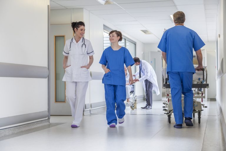 Male,Nurse,Pushing,Stretcher,Gurney,Bed,In,Hospital,Corridor,With