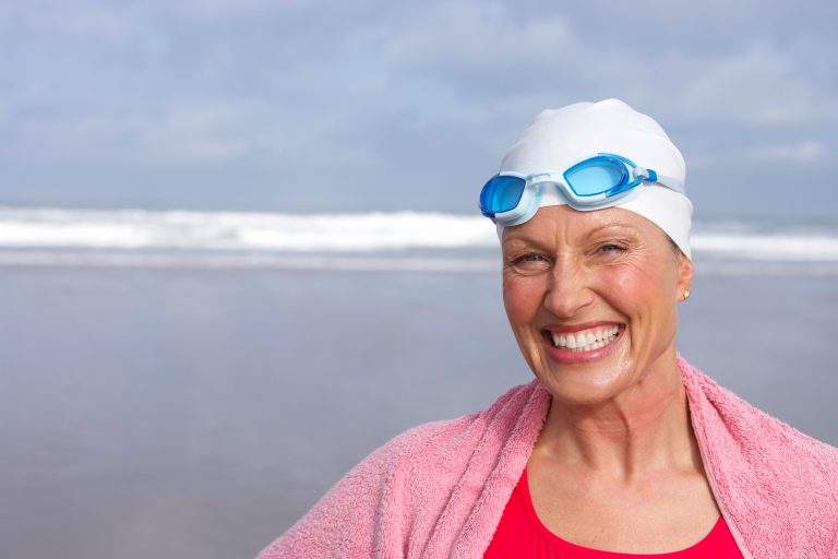Senior,Woman,In,Bathing,Suit,Smiling,At,Beach