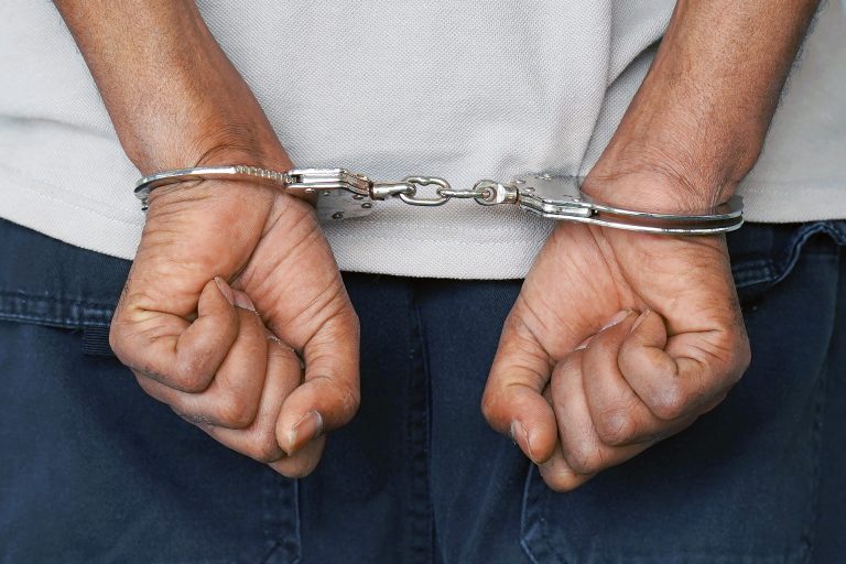 Close-up.,Arrested,Man,Handcuffed,Hands,At,The,Back,Isolated,On