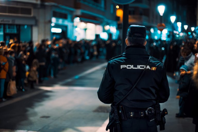 Rear,View,Of,Police,Officer,Watching,During,Crowded,Religious,Event.
