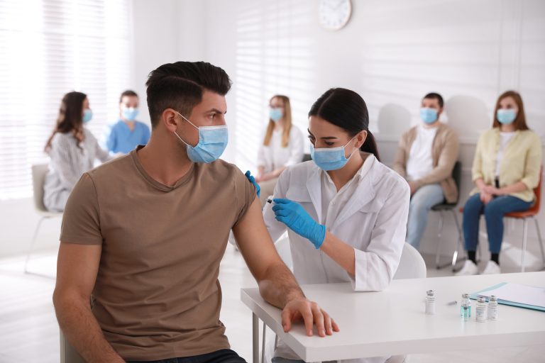Doctor,Giving,Injection,To,Patient,While,Other,Waiting,In,Line