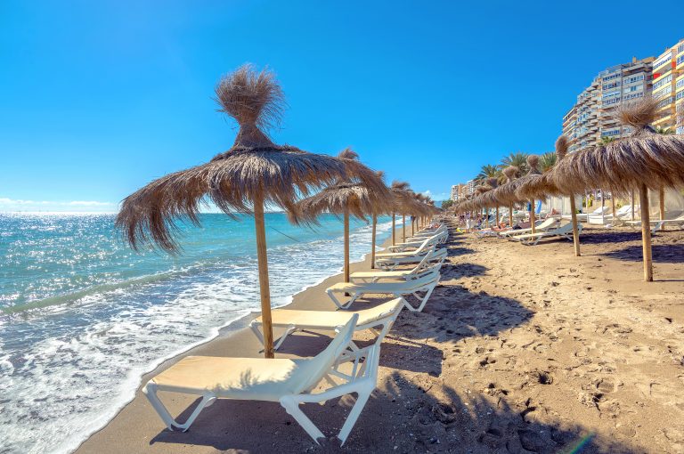 Lounge,Chairs,And,Straw,Umbrellas,At,The,Beach,In,Malaga.