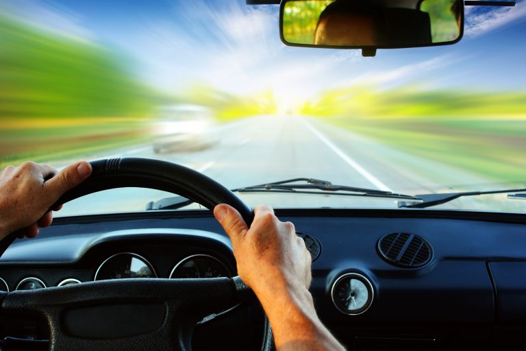 Hands,On,Steering,Wheel,Of,A,Car,Driving,On,An