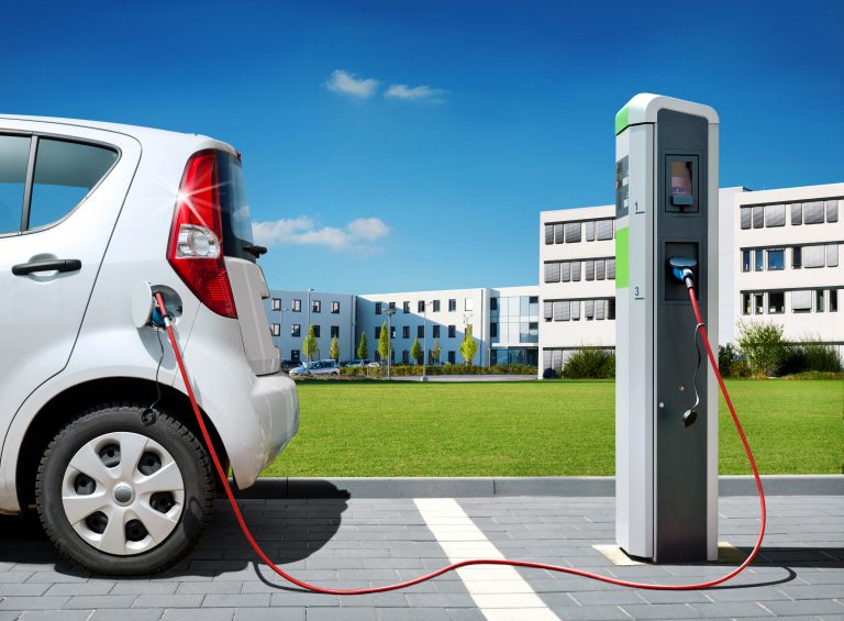 Electric,Car,On,Charging,Spot,In,Front,Of,Architecture,Office