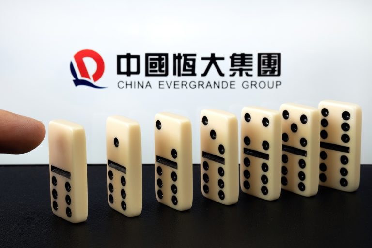 Finger,Touching,Domino,Blocks,And,Blurred,China,Evergrande,Group,Logo.