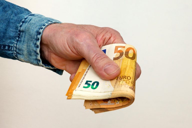 A,Man's,Hand,Holds,Out,A,Bundle,Of,Fifty,Euro