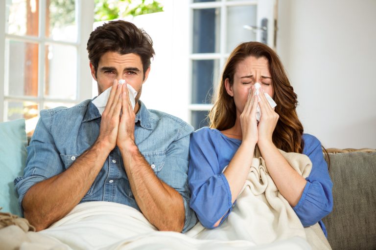Young,Couple,Blowing,Their,Nose,In,Tissue,At,Home