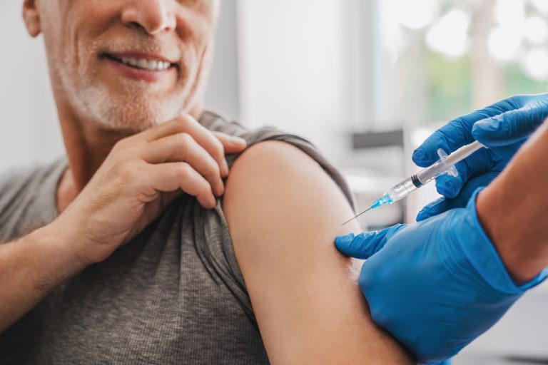 Doctor,Making,Injection,To,Senior,Patient,In,Clinic