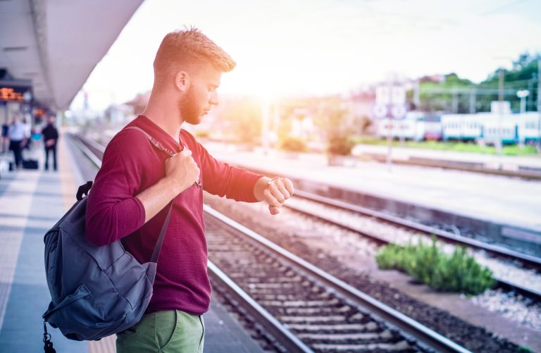Young,Man,Checking,The,Time,On,Wristwatch,At,Rail,Station