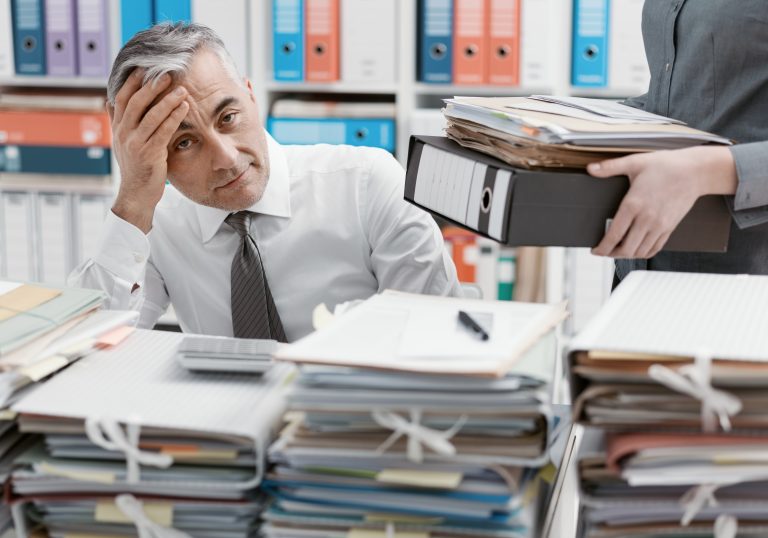 Stressed,Businessman,Working,At,Office,Desk,And,Overloaded,With,Work,