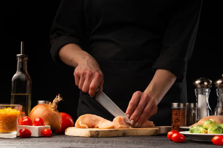 Chef,Slices,Chicken,,For,Cooking,,And,Salad.,Against,The,Background