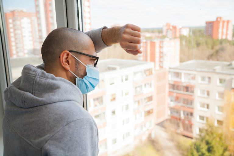 Man,In,Medical,Mask,Looking,Through,The,Window.,Isolation,At