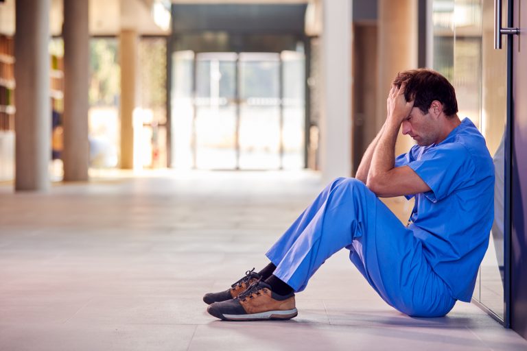 Tired,And,Overworked,Medical,Worker,In,Scrubs,Sitting,On,Floor