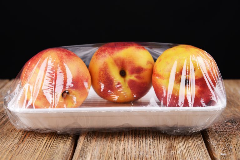 Peaches,Packed,In,Food,Film,On,Table,On,Black,Background
