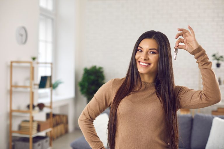 Happy,Woman,Holding,Keys,To,New,Home,,Looking,At,Camera