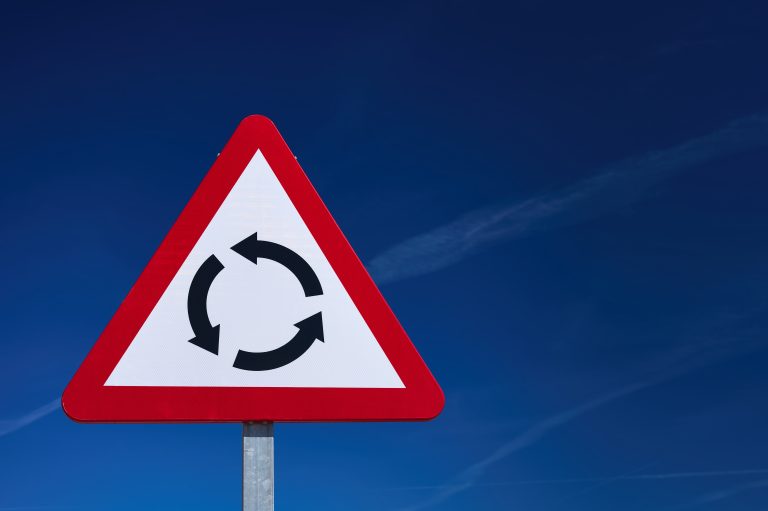 Detail,Of,A,Triangular,Roundabout,Warning,Sign,Over,A,Blue