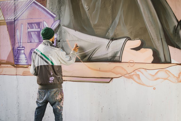 Graffiti,Artist,Painting,With,Aerosol,Spray,On,The,Wall
