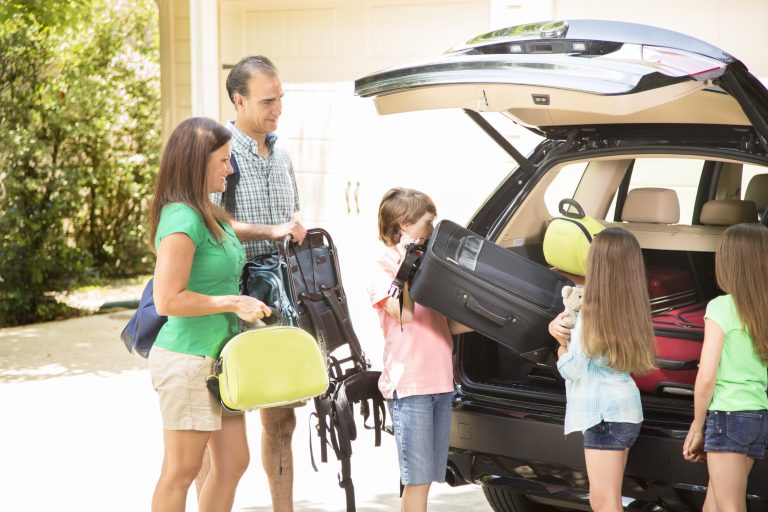 Family packing car to go on summer vacation. Parents, children.