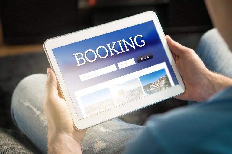 Booking,App,Or,Website,On,Tablet,Screen.,Man,Searching,Hotel
