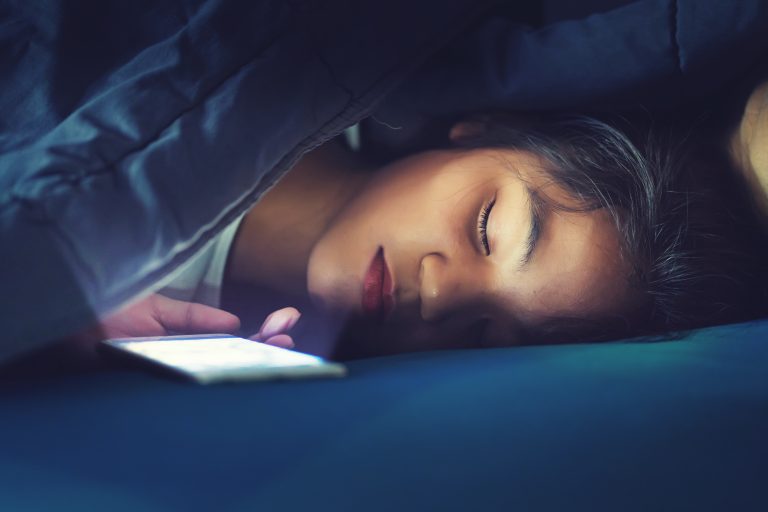 Teen,Girl,Sleeping,In,Bed,With,Smart,Phone,Under,Blanket