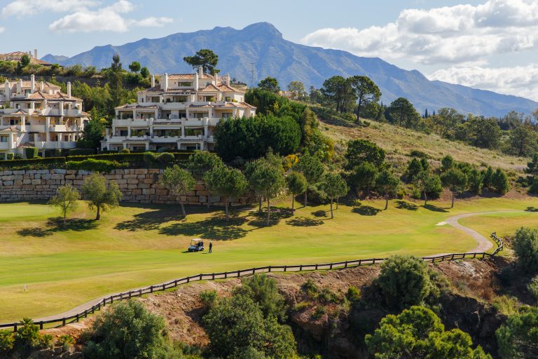 Modern,Hauses,And,Green,Golf,Field,On,Mountains,Against,Cloudy