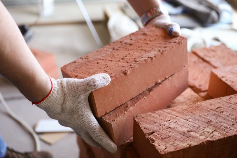 Close-up,Of,Male,Hands,Lifting,Several,Red,Bricks,At,Construction