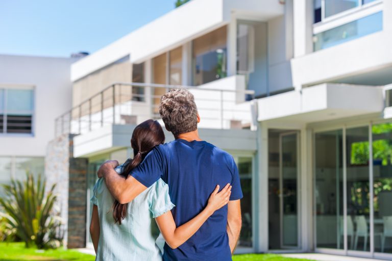 Couple,Embracing,In,Front,Of,New,Big,Modern,House,,Outdoor
