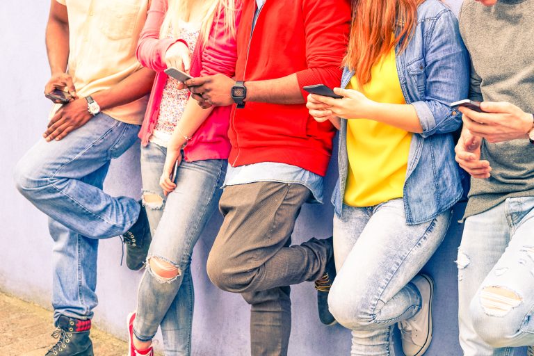 Multiracial,Group,Of,Friends,Texting,Sms,And,Looking,Down,To