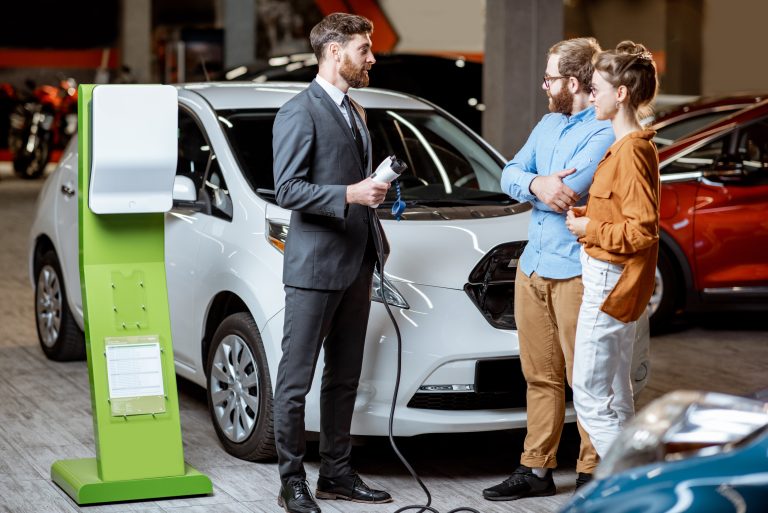 Sales,Manager,Showing,Car,Charging,Station,To,A,Young,Couple,