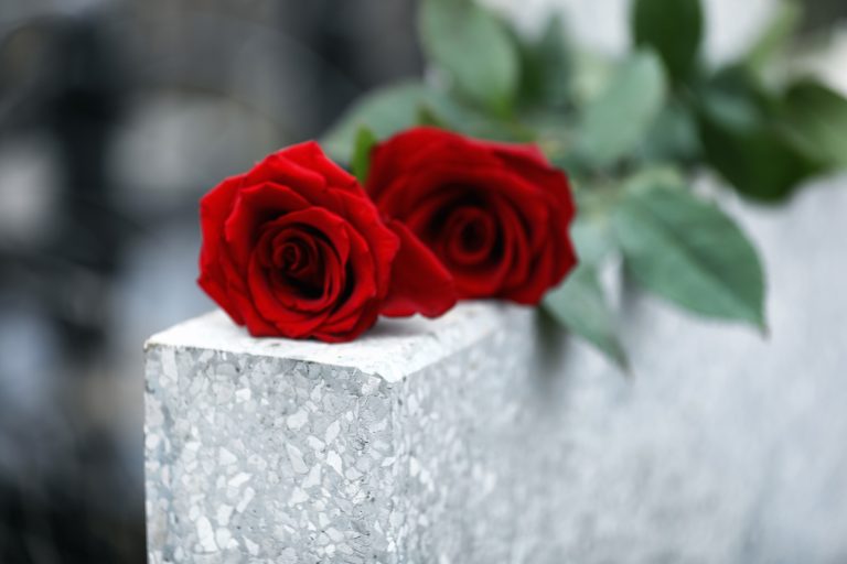 Red,Roses,On,Light,Grey,Tombstone,Outdoors,,Closeup.,Funeral,Ceremony