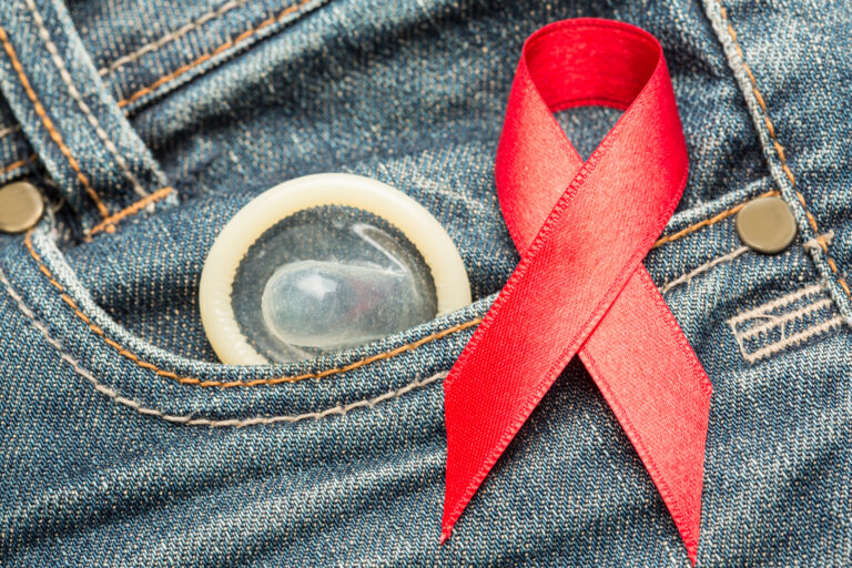 Condom,Peeking,Out,From,Jeans,Pocket,With,Red,Awareness,Ribbon