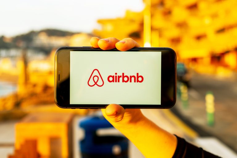 Hands,Holding,Iphone,11,With,An,App,Of,Airbnb,Service.