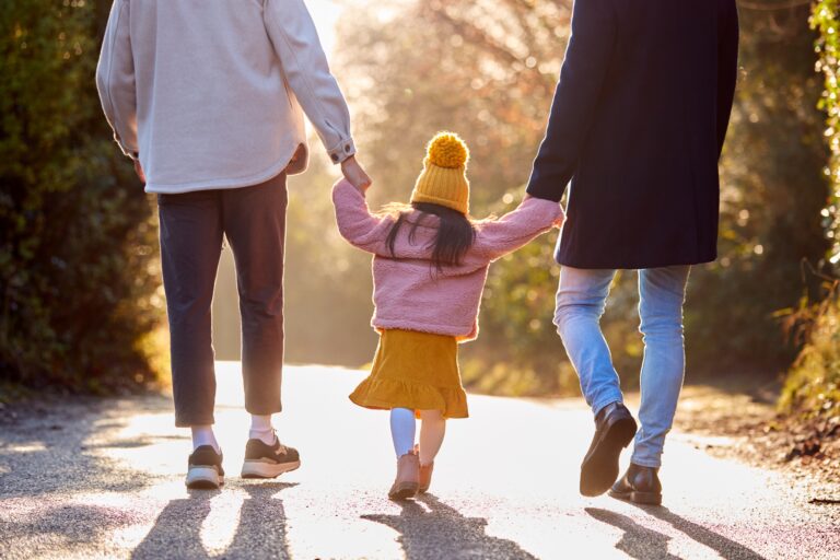 Rear,View,Of,Family,With,Two,Dads,Taking,Daughter,For