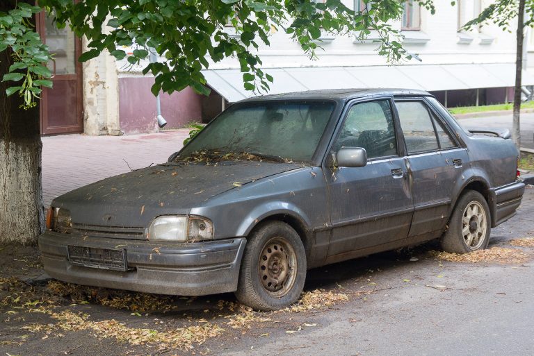 Rusty,Abandoned,Car,On,A,City,Street