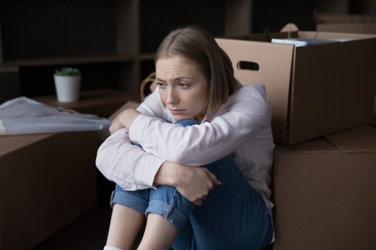 Sad,Young,Woman,Sits,Near,Heap,Of,Cardboard,Boxes,With