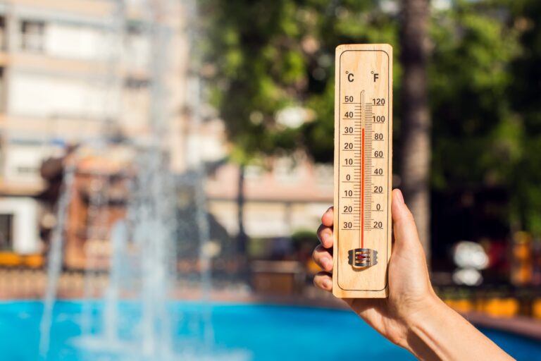 Hot,Weather.,Thermometer,In,Hand,In,Front,Of,Fountain,During