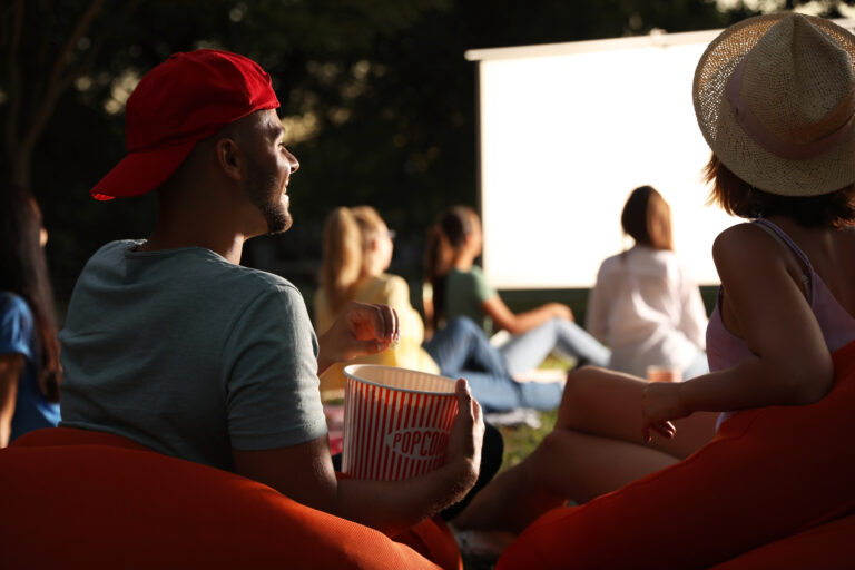 Young,Couple,With,Popcorn,Watching,Movie,In,Open,Air,Cinema.