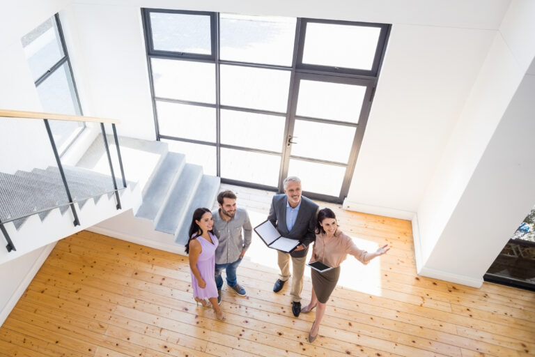 Real,Estate,Agent,Showing,New,House,To,Couple,With,Digital