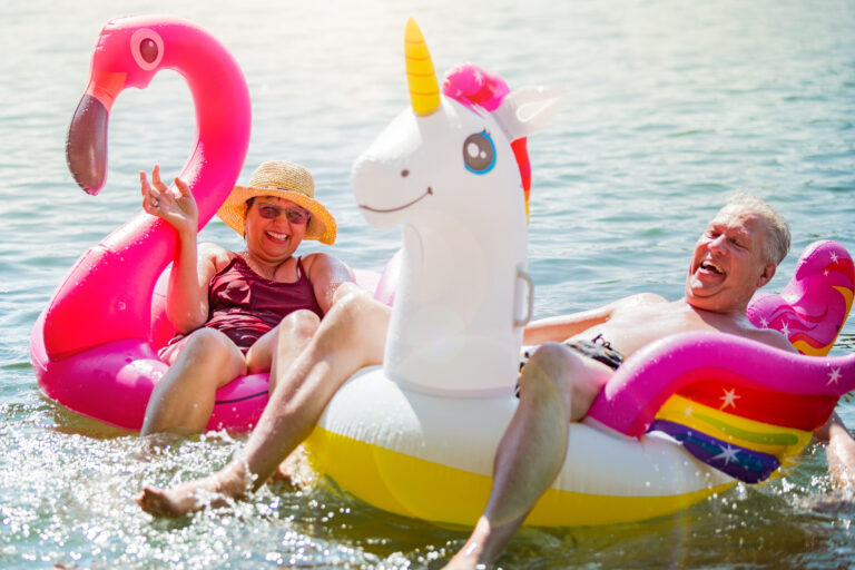 Elderly,Couple,Having,Fun,On,Inflatable,Flamingo,And,Unicorn.,Funny