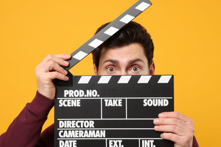 Surprised,Actor,Holding,Clapperboard,On,Orange,Background