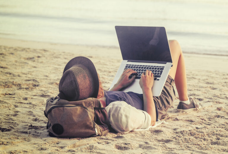 Young,Woman,Using,Laptop,Computer,On,A,Beach.,Freelance,Work
