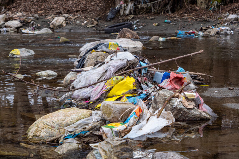Close,Up:,Pile,Of,Plastic,Waste,Jammed,Between,The,Rocks