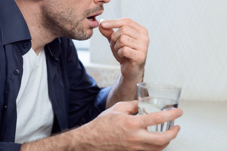Unrecognizable,Sick,Man,Taking,Pill,Holding,Glass,Of,Water,At