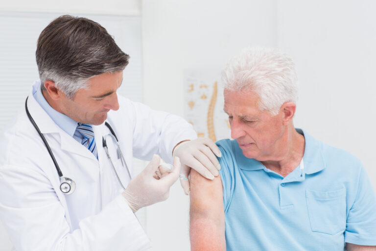 Male,Doctor,Injecting,Senior,Patient,In,Clinic