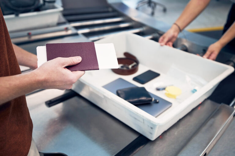 Passenger,Holding,Passport,Against,Personal,Items,,Liquids,,And,Laptop,In
